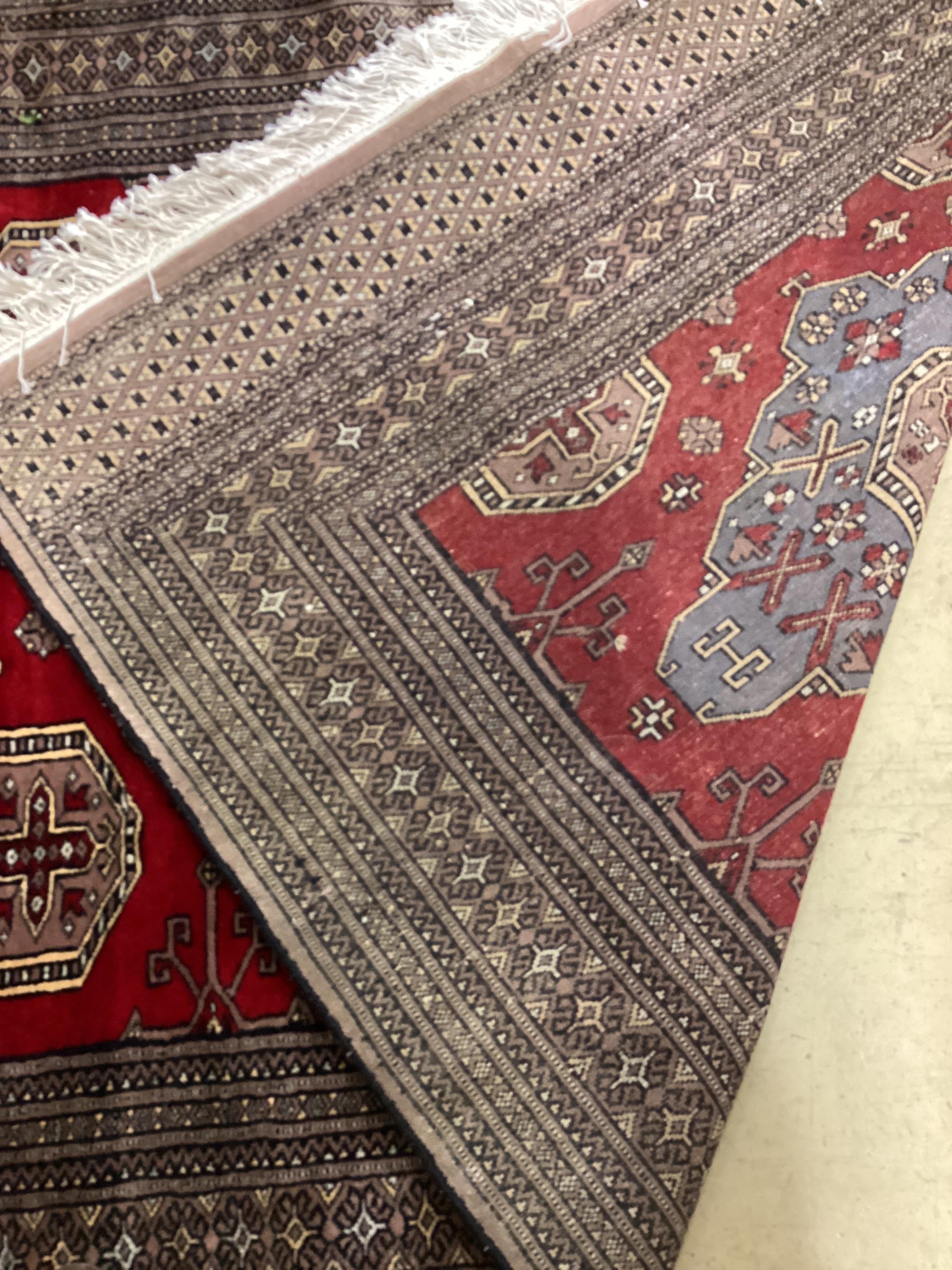 A Pakistan red ground triple medallion rug, 200cm x 126cm.
